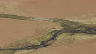 Green river tracing its way on a desert soil
