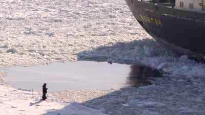 Huge nuclear-powered icebreaker and small fisherman on icy Ienissei river