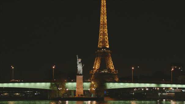 The Parisian Statue of Liberty and the Eiffel Tower, seen from a boat at night.